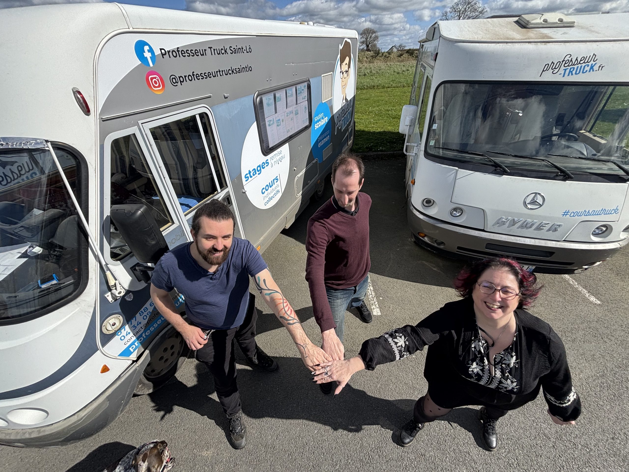 Trois professeurs réunis devant plusieurs camping-cars Professeur Truck en Normandie.