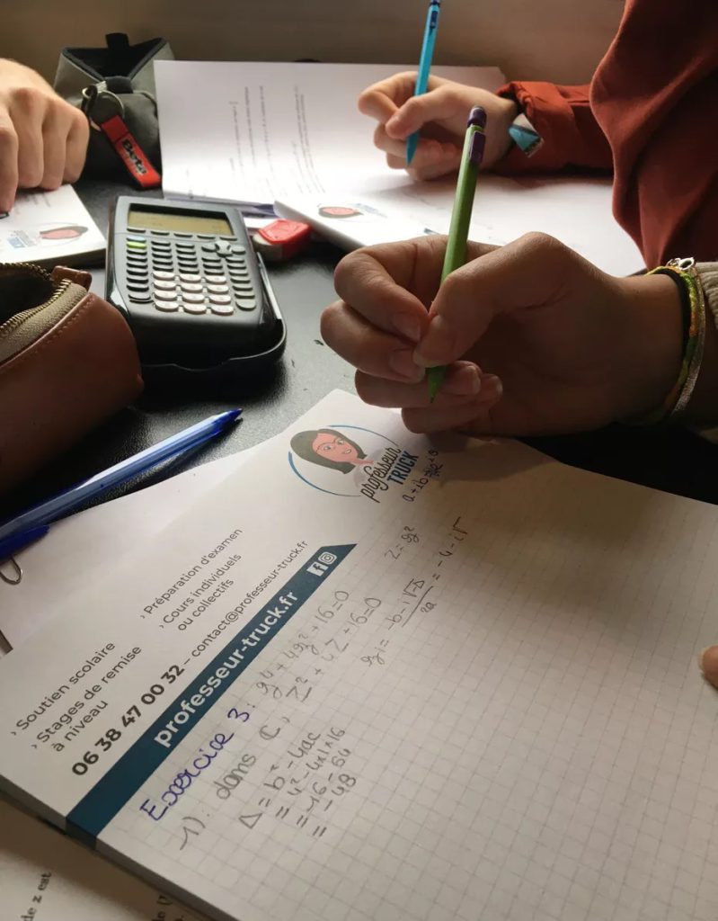 Deux élèves écrivent leurs exercices à côté d’une calculatrice.